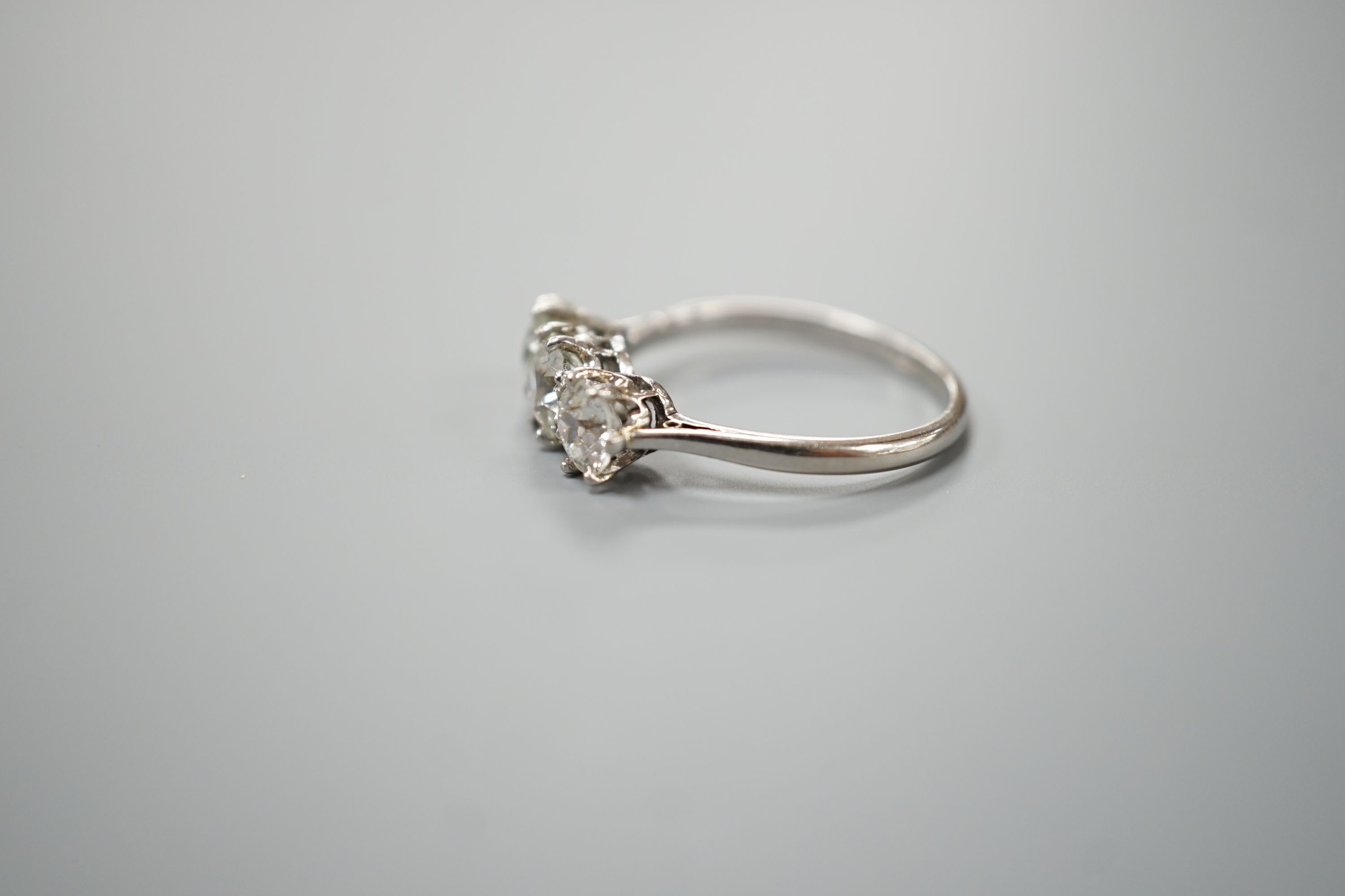 A white metal (stamped Plat) and three stone diamond set ring, size P/Q, gross weight 3.7 grams